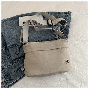 Detail of beige nylon crossbody bag with adjustable strap and metal floral logo
