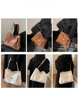 Detail view of large PU leather tote bags in brown and beige with gold chain straps