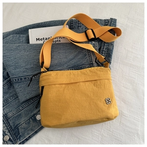 Detail of yellow nylon passport bag with silver clover logo on denim background