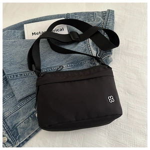 Detail of black nylon travel passport bag with silver clover logo on denim background