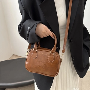 Brown leather bowling bag with lucky embossed details and gold metal hooks