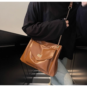 Detail of vintage brown shoulder bag featuring gold chain strap and turn-lock closure
