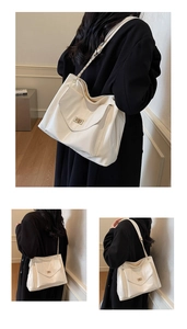Close-up of beige tote bag with a golden turn-lock clasp and polished faux leather texture