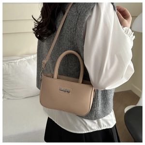 Detail of a beige mini leather bag with a silver brand logo and adjustable strap