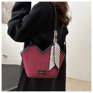 Detail of burgundy velvet tote bag with scarf handle and black fashion label on coat