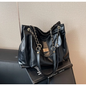 Détail du grand sac cabas noir avec chaîne dorée et fermoir pivotant sur magazine