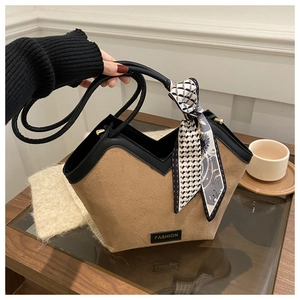 Detail of a brown suede tote bag featuring a V-shaped top edge and silk scarf handle wrap