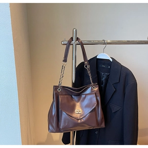 Detail of dark brown leather tote featuring chain strap and gold twist lock pocket