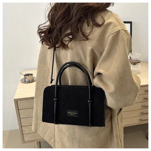 Macro detail of black corduroy shoulder bag with leather logo tag and elegant texture
