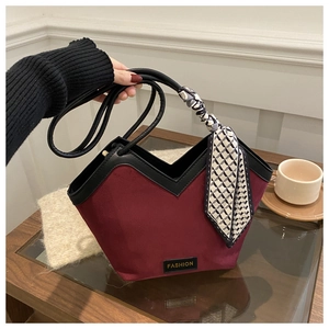 Detail of burgundy suede tote bag featuring a decorative silk scarf and metallic label