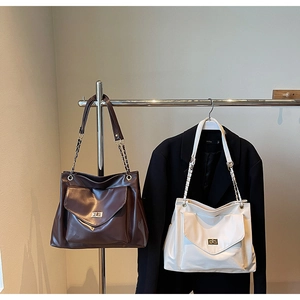 Detail view of large leather tote bags with metal chain straps and front flap pocket