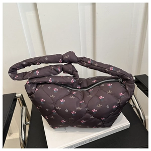 Détail d'un sac à main marron foncé en nylon matelassé avec fleurs et poignée nouée