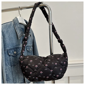 Détail du sac dumpling en nylon noir matelassé avec imprimé floral et lettrage chic
