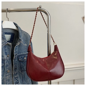 Dettaglio della borsa a mezzaluna bordeaux vintage in pelle lucida con tracolla a catena