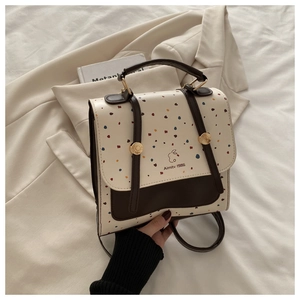 Detailed view of polka dot backpack with Aimity 1986 logo and metal buckle on suit