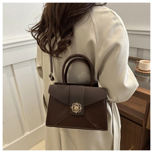 Detail of dark brown leather handbag with vintage gold buckle and elegant stitching