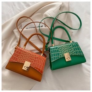 Detail of crocodile embossed flap on leather bags with gold metal clasps in two colors