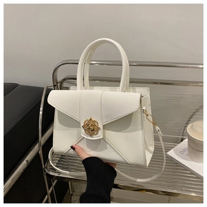 Close-up of cream faux leather handbag featuring decorative gold vintage metal lock and handle