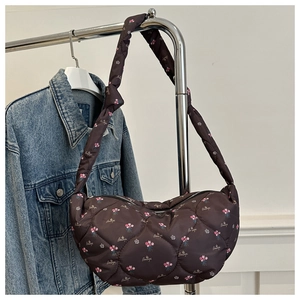 Détail du sac demi-lune matelassé marron foncé avec motif floral et texte sur nylon