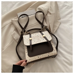 Detailed view of bicolor polka dot leather backpack featuring a top handle and logo