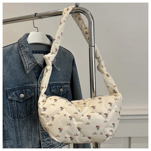 Gros plan du sac en nylon matelassé beige avec motifs floraux et bandoulière nouée
