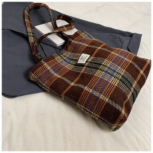 Close-up of brown plaid wool tote bag with white woven label and textured fabric detail