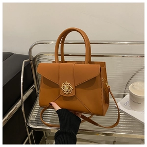 Detail of orange-brown leather bag featuring a gold geometric floral cutout twist lock