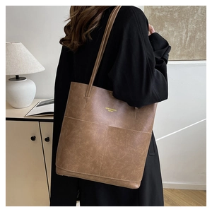 Detail of vintage brown leather tote bag showing gold logo and premium textured material