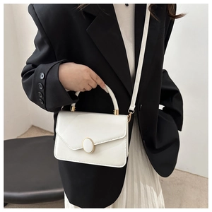 Detail der cremeweißen Kunstledertasche mit elegantem goldenem ovalen Drehverschluss