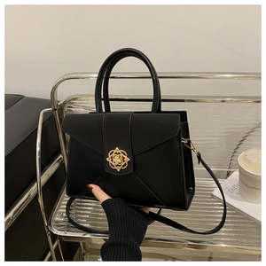 Detail of black matte leather handbag featuring an intricate gold geometric floral clasp