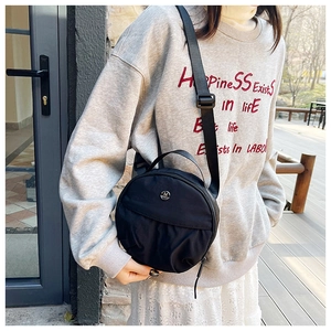 Detail of black round nylon crossbody bag showing pleated texture and metal logo