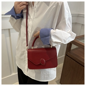 Détail du sac bandoulière vintage rouge avec boucle ovale en métal et texture cuir