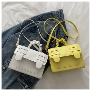 Detail of white and yellow crossbody bags with pleated handles on denim background