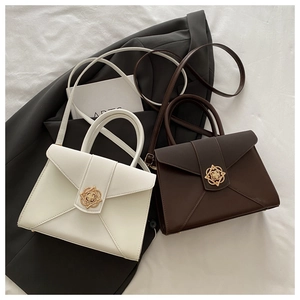 Detail of minimalist leather handbag with elegant golden flower-shaped geometric metal lock