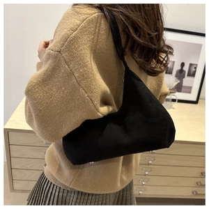 Elegant black suede crescent shoulder bag styled with a neutral knit outfit and skirt