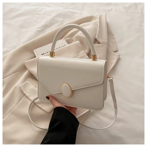 Détail du sac bandoulière crème en cuir avec boucle dorée et poignée supérieure