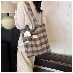 Detail of large plaid wool tote bag with white cloud plush pendant and HOU label
