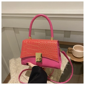 Detail der Stein-Prägung auf der pink-orangen Umhängetasche mit goldener Schließe