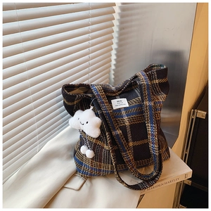 Detailed texture of plaid wool tote bag with a cute white plush cloud charm accessory