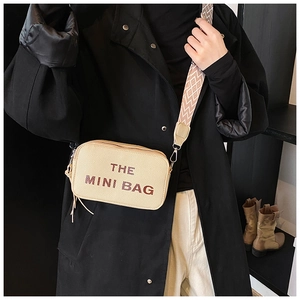 Close-up of beige mini camera bag featuring Marc-style lettering and geometric strap