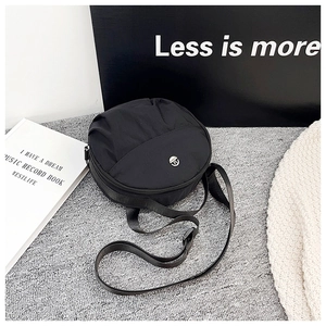 Detail of round nylon crossbody bag with metal logo and adjustable shoulder strap
