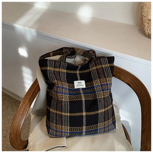 Detail of checkered tweed tote bag with blue and brown patterns on a vintage wooden chair