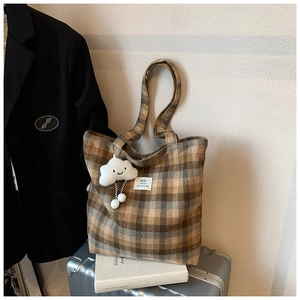 Detail of plaid tote bag with cloud charm on a silver suitcase for winter casual style