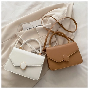 Détail de sacs bandoulière crème et camel avec boucles métalliques dorées ovales