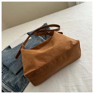 Detail of caramel suede shoulder bag with adjustable leather strap and gold buckle