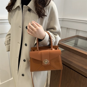 Minimalist brown leather crossbody handbag with golden floral hardware on model