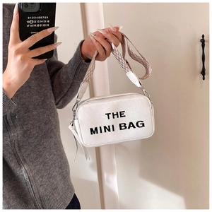 Close-up of white textured leather mini bag featuring bold The Mini Bag lettering