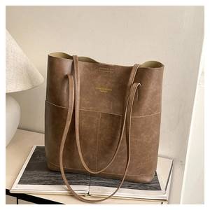Detail of a large brown tote bag with textured faux leather and gold lettering