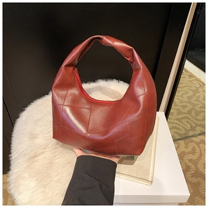 Close-up of deep red hobo bag with geometric patchwork and wide integrated handle