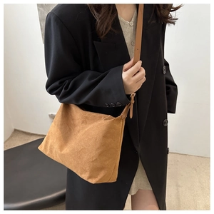 Detailed side view of caramel suede tote bag featuring slim leather straps and matte texture